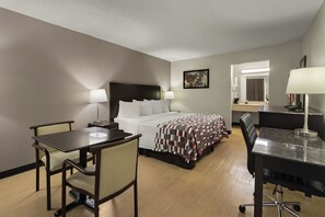 Una habitación de hotel con cama, escritorio, silla y una mesita.
