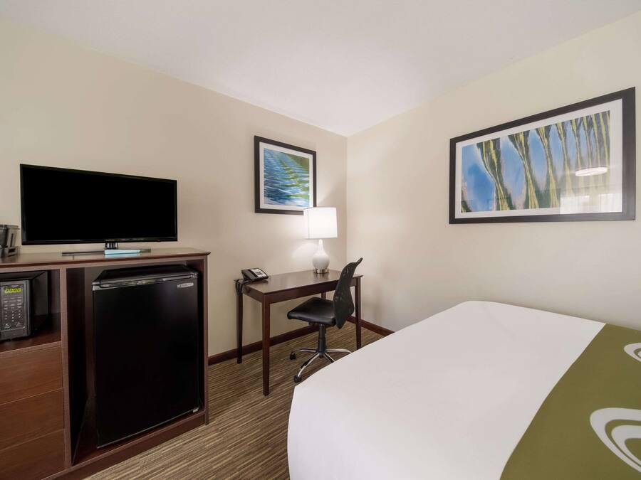 Ein Hotelzimmer mit Bett, Schreibtisch mit Lampe, Fernseher, Minikühlschrank und Mikrowelle.