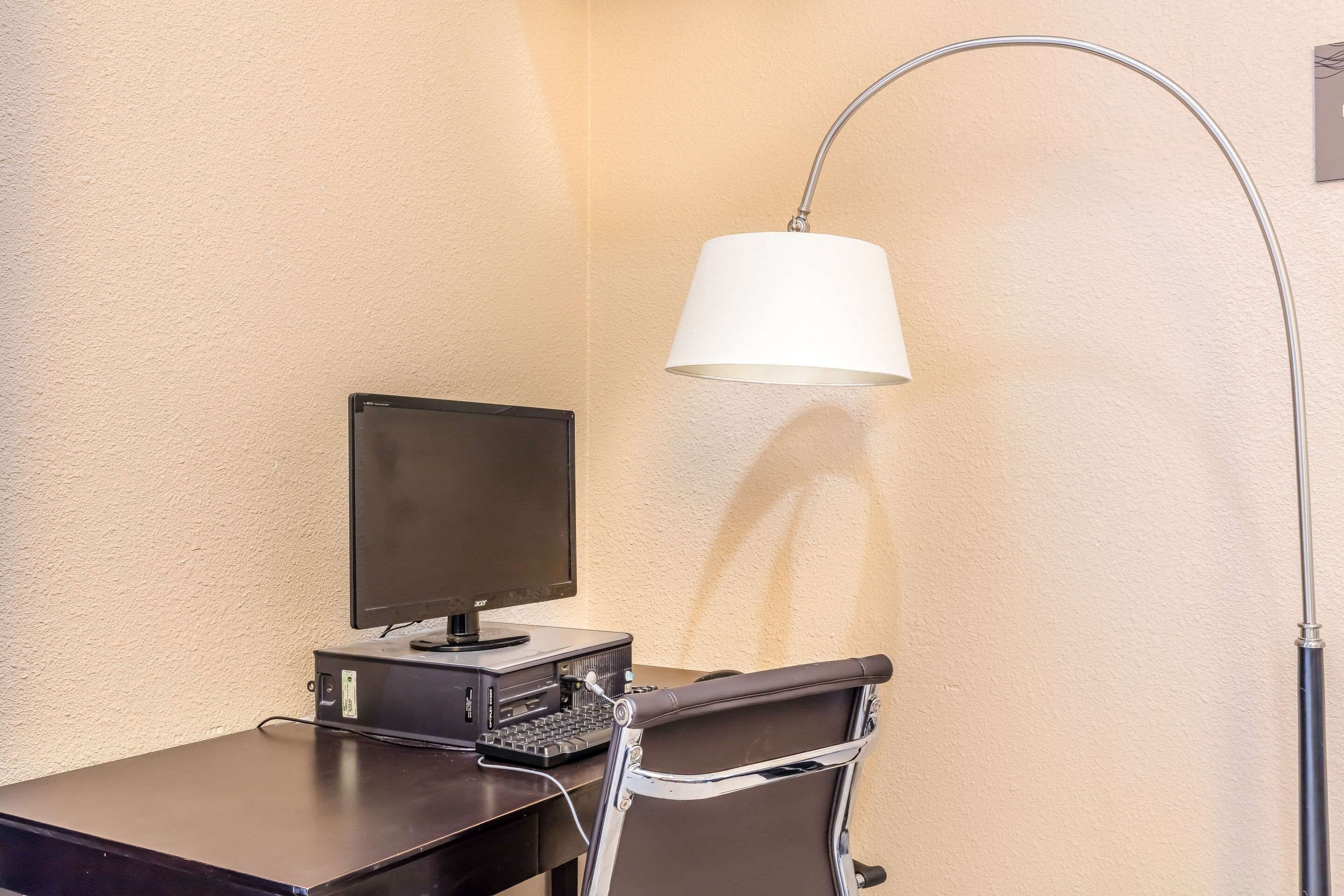A workspace with a desk, a computer monitor, keyboard, and a chair.