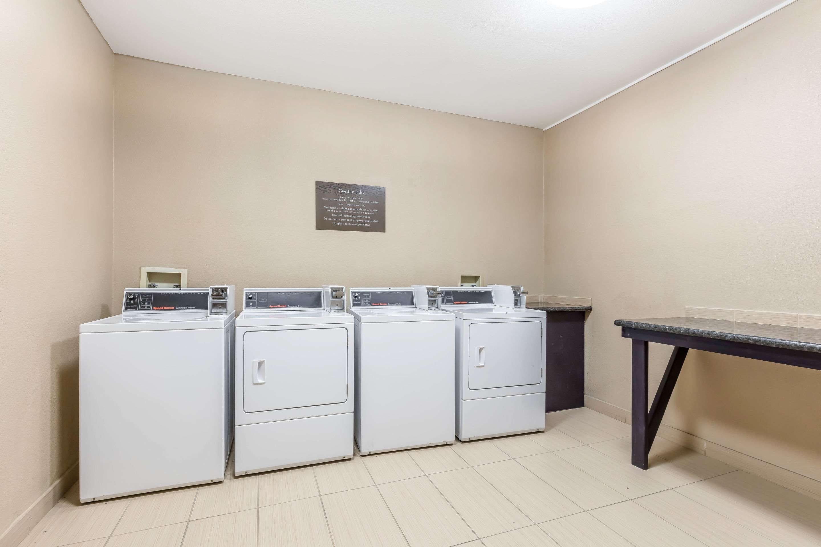 A laundry area with four white washing machines and a table.