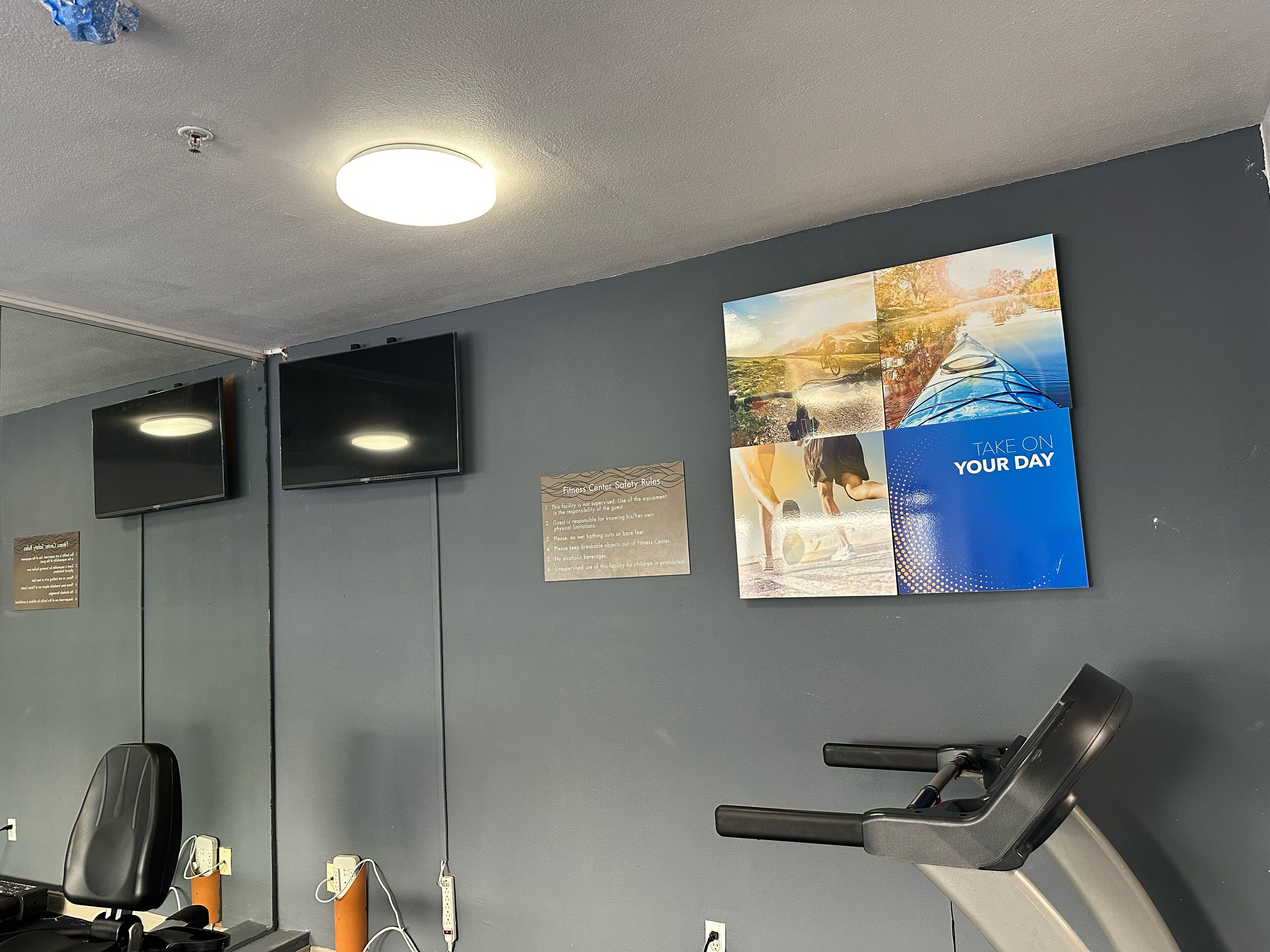 A gym with exercise equipment, a treadmill, and a wall-mounted TV.