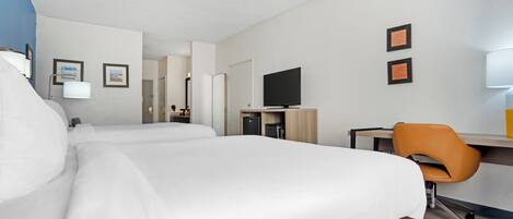 A hotel room with two beds, a desk with a chair, a television, and framed pictures on the wall.