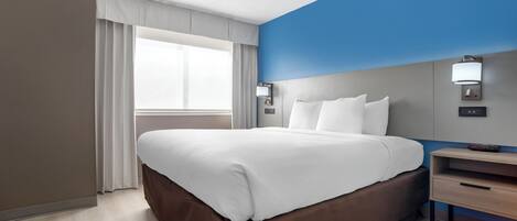 Quarto de hotel moderno com uma cama grande, uma mesa de cabeceira e um criado-mudo.