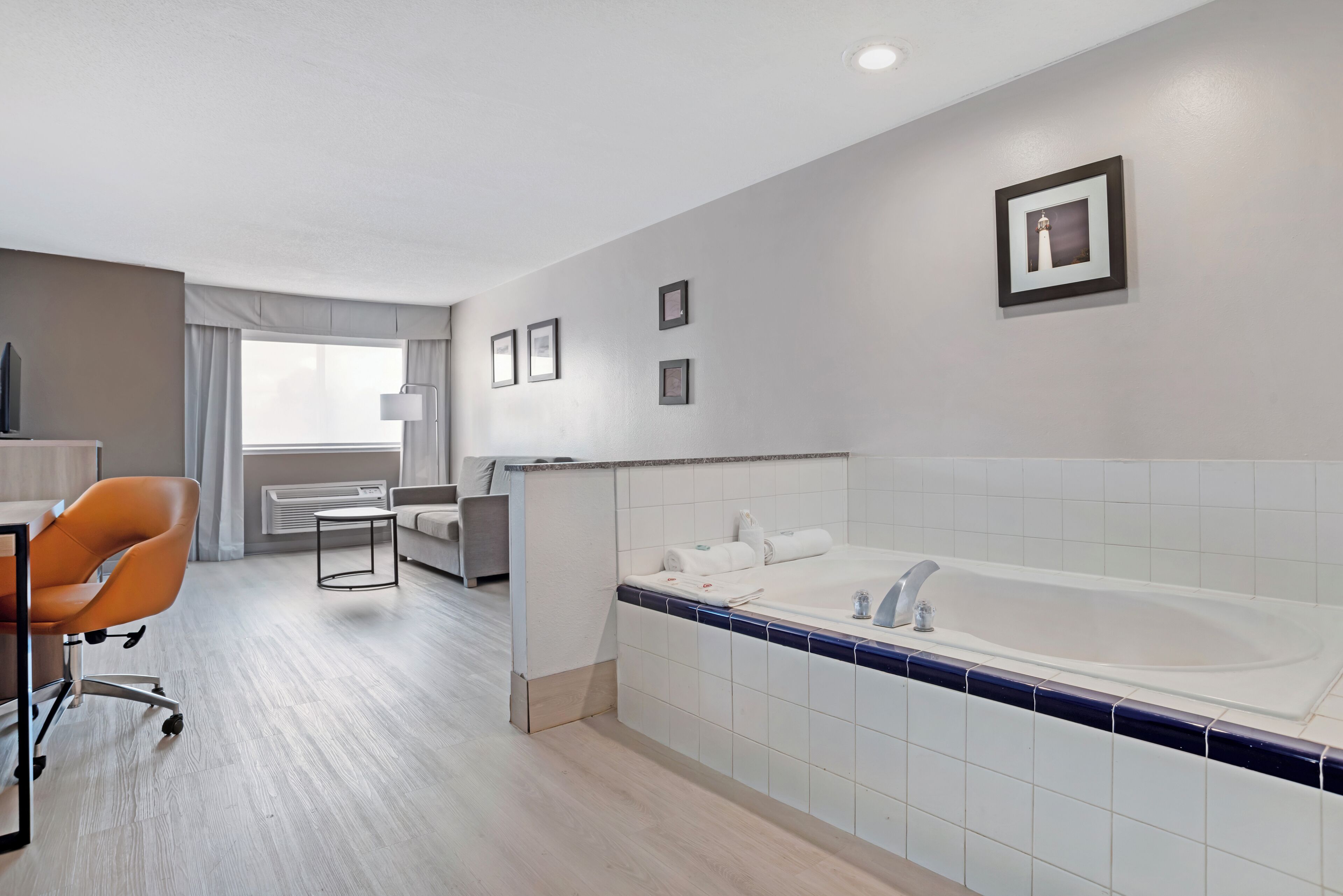 A modern hotel room with a large bathtub, a desk with a chair, and a bed.