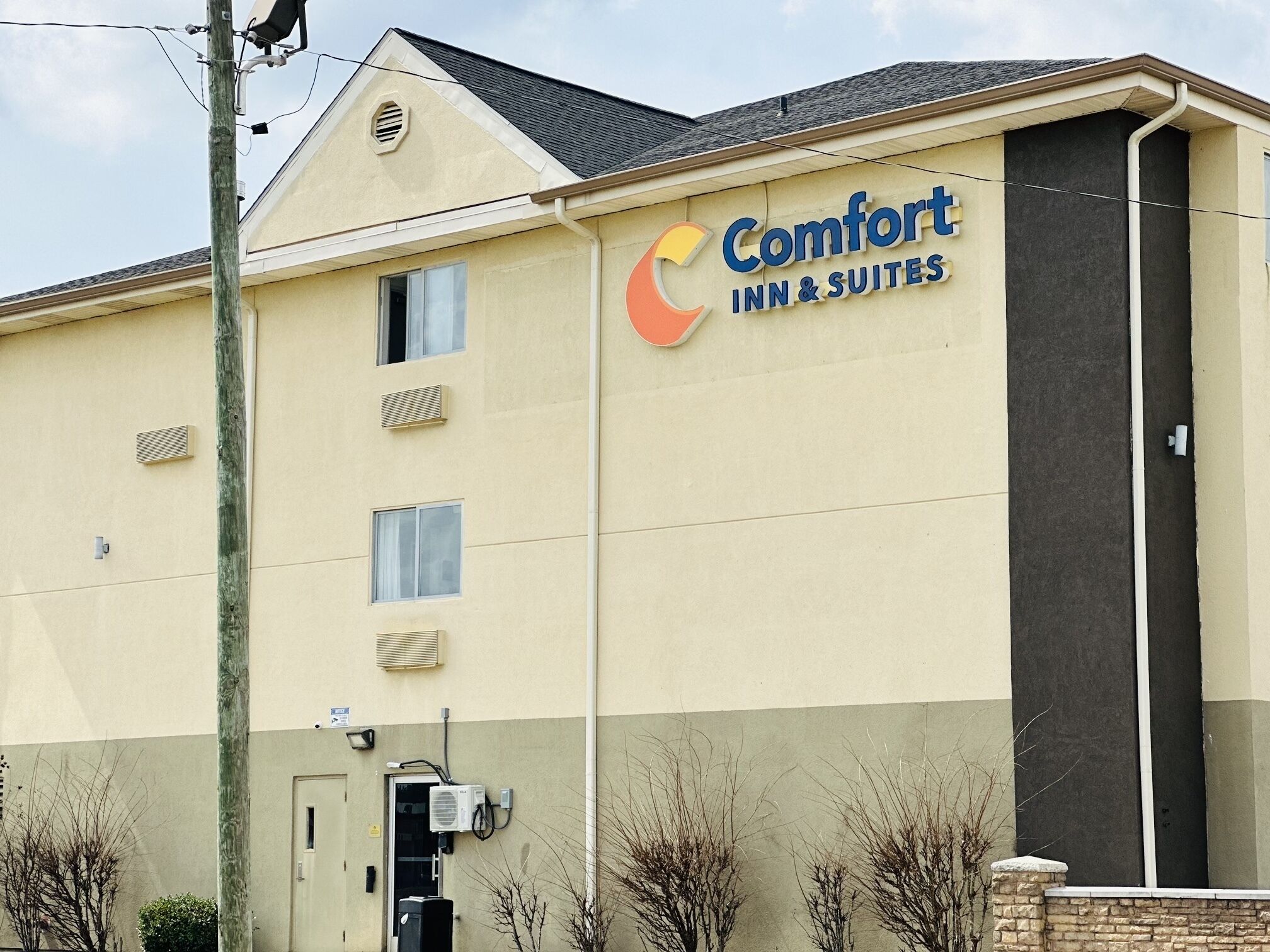 A Comfort Inn & Suites building with a beige facade, multiple windows, and a large sign displaying the logo.