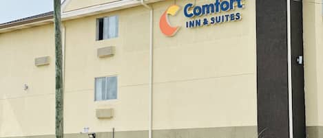 Een Comfort Inn & Suites gebouw met een beige gevel, meerdere ramen en een groot bord met het logo.