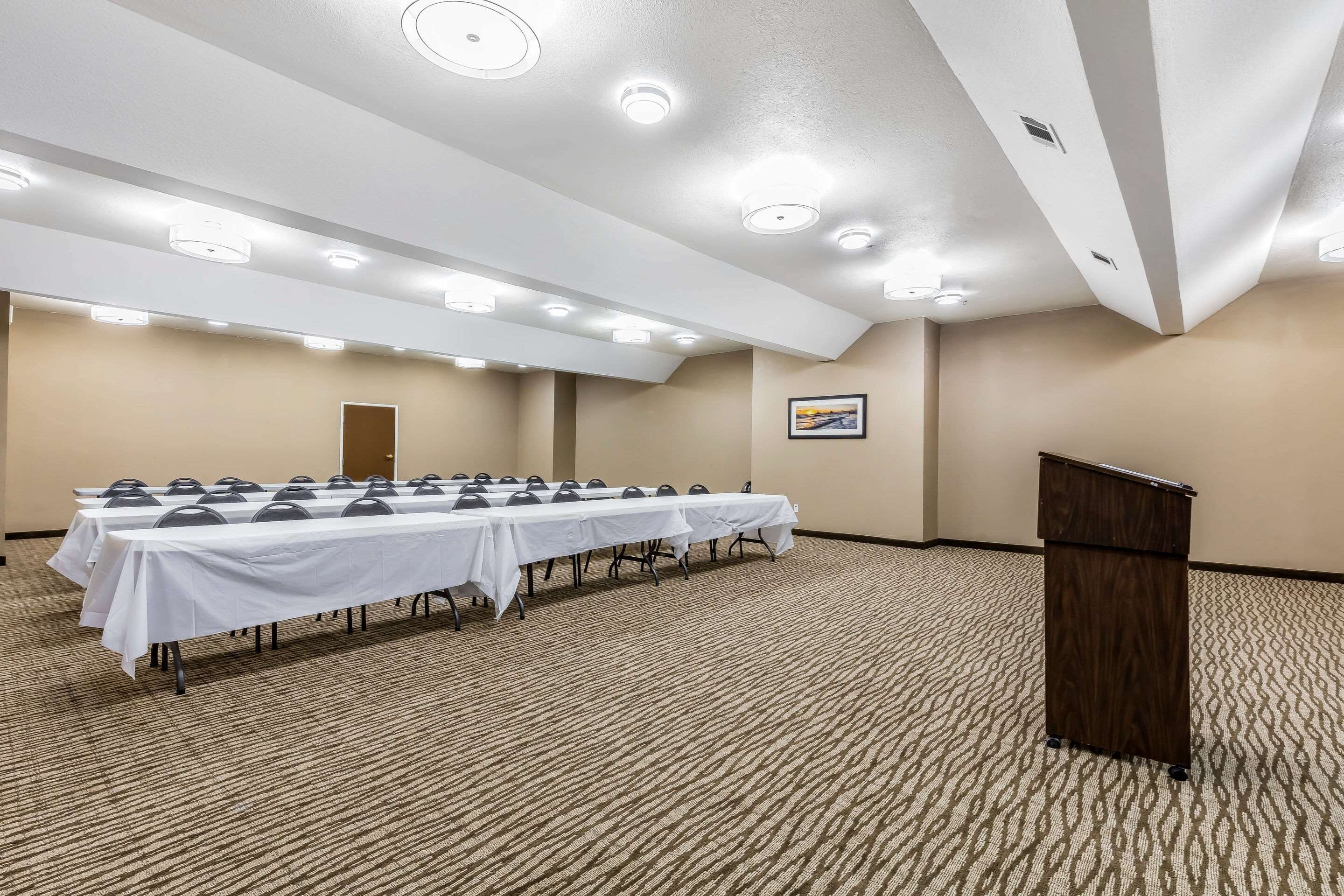 Une salle de conférence avec une longue table, des chaises et un pupitre.
