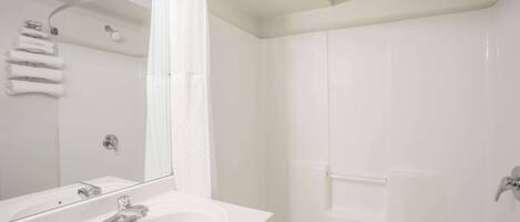 A modern bathroom with a white sink, mirror, and shower area.