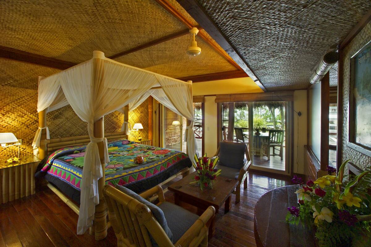 A room with a four-poster bed, wooden furniture, and a view of the outdoors.