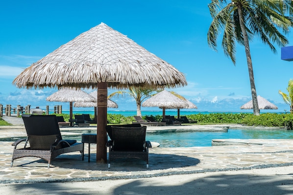 Una piscina al aire libre, sillones reclinables de piscina