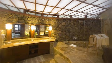 Relax in a serene bathroom with a large mirror, dual sink vanity, and stone bench.