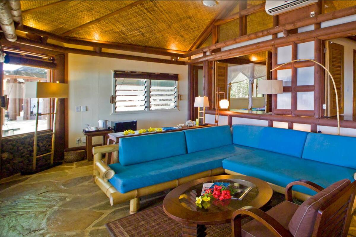 A room with a blue sofa, a round coffee table, and a stone wall.