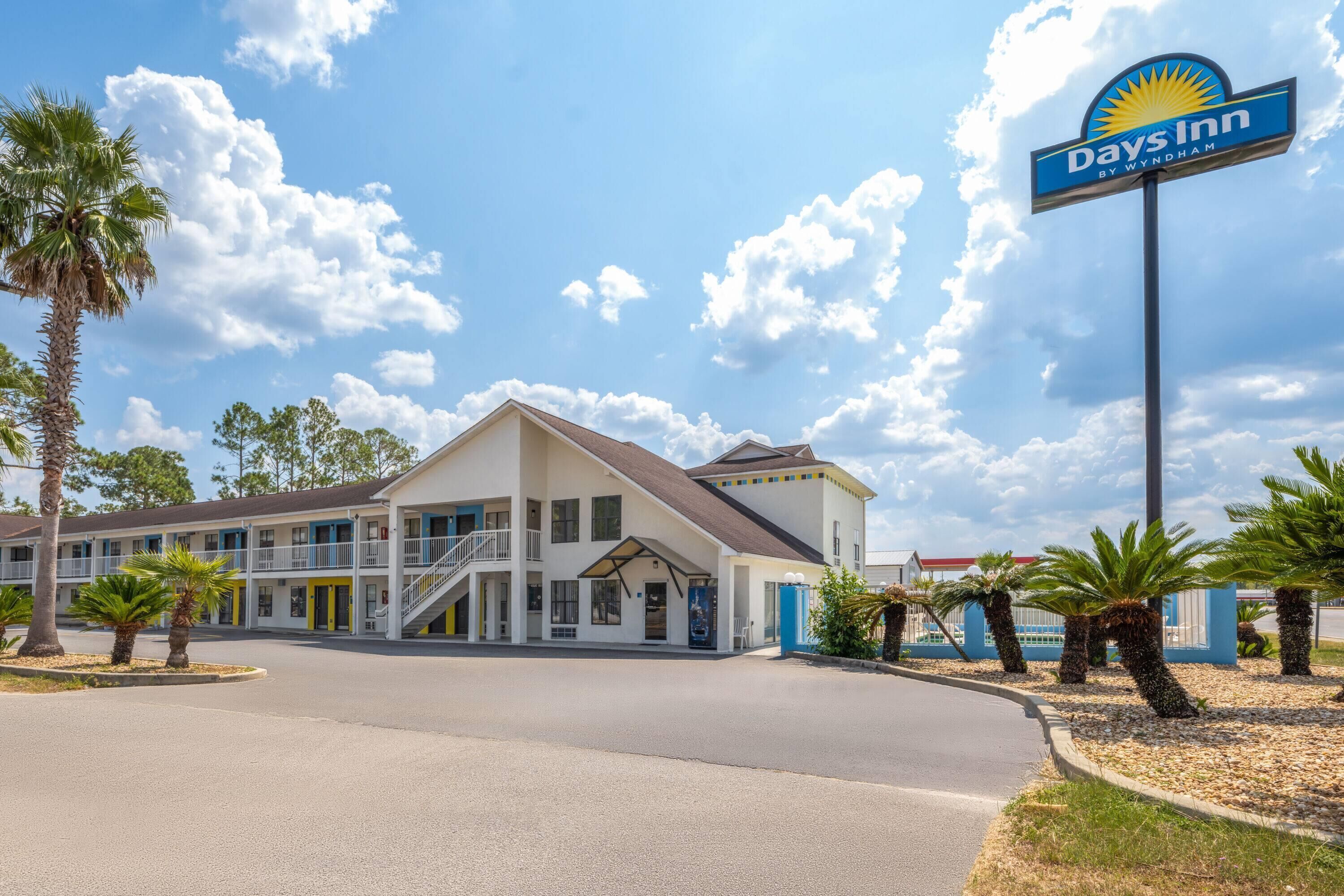 Un motel Days Inn con un edificio de dos pisos, un acceso cubierto y un estacionamiento.