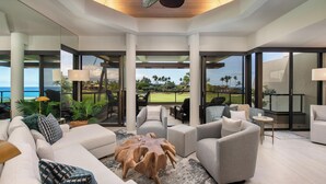 Un soggiorno moderno con un'ampia vetrata che dà su un balcone con vista su un campo da golf.
