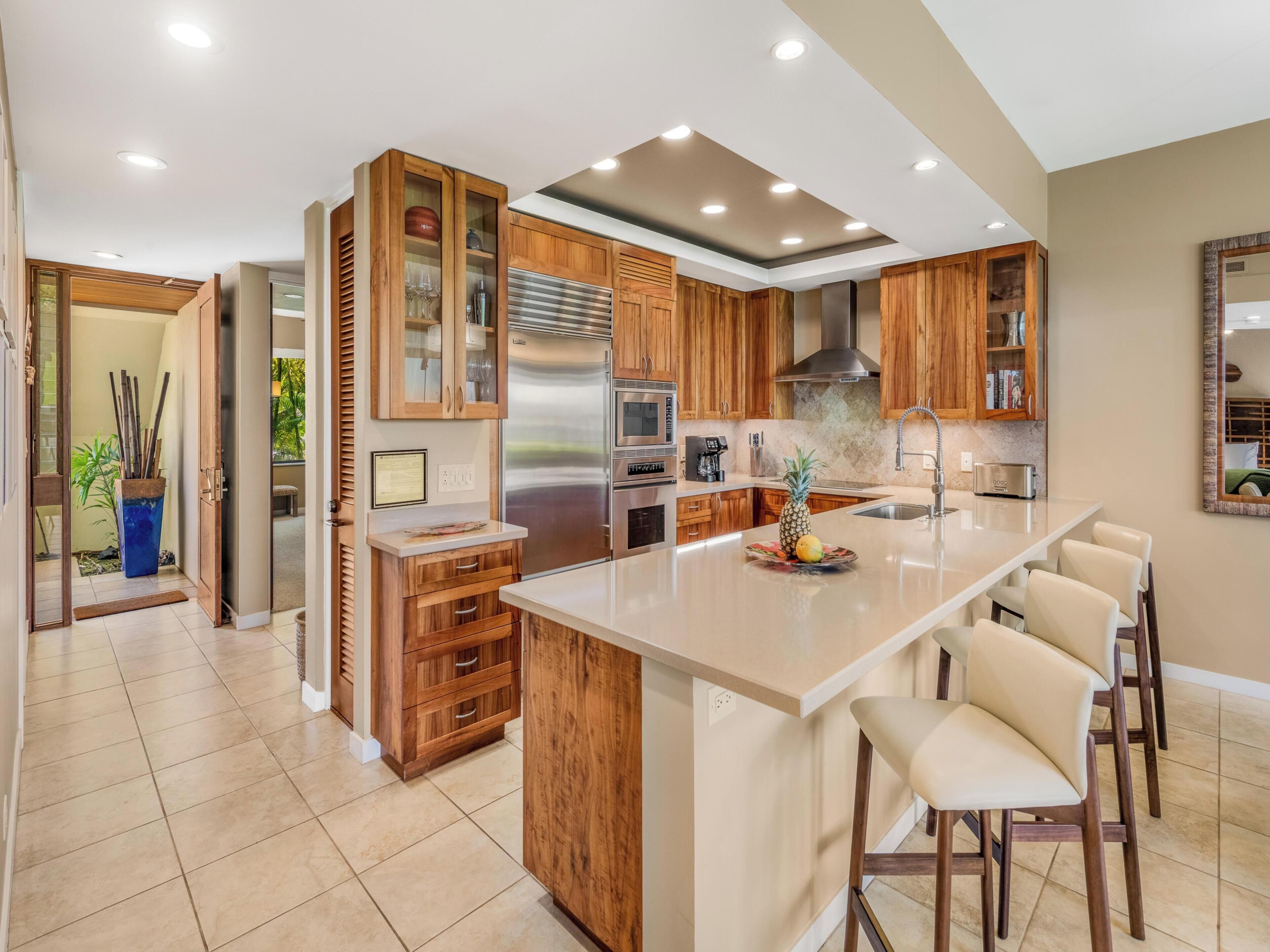A modern kitchen with wooden cabinets, stainless steel appliances, and a central island with bar stools.