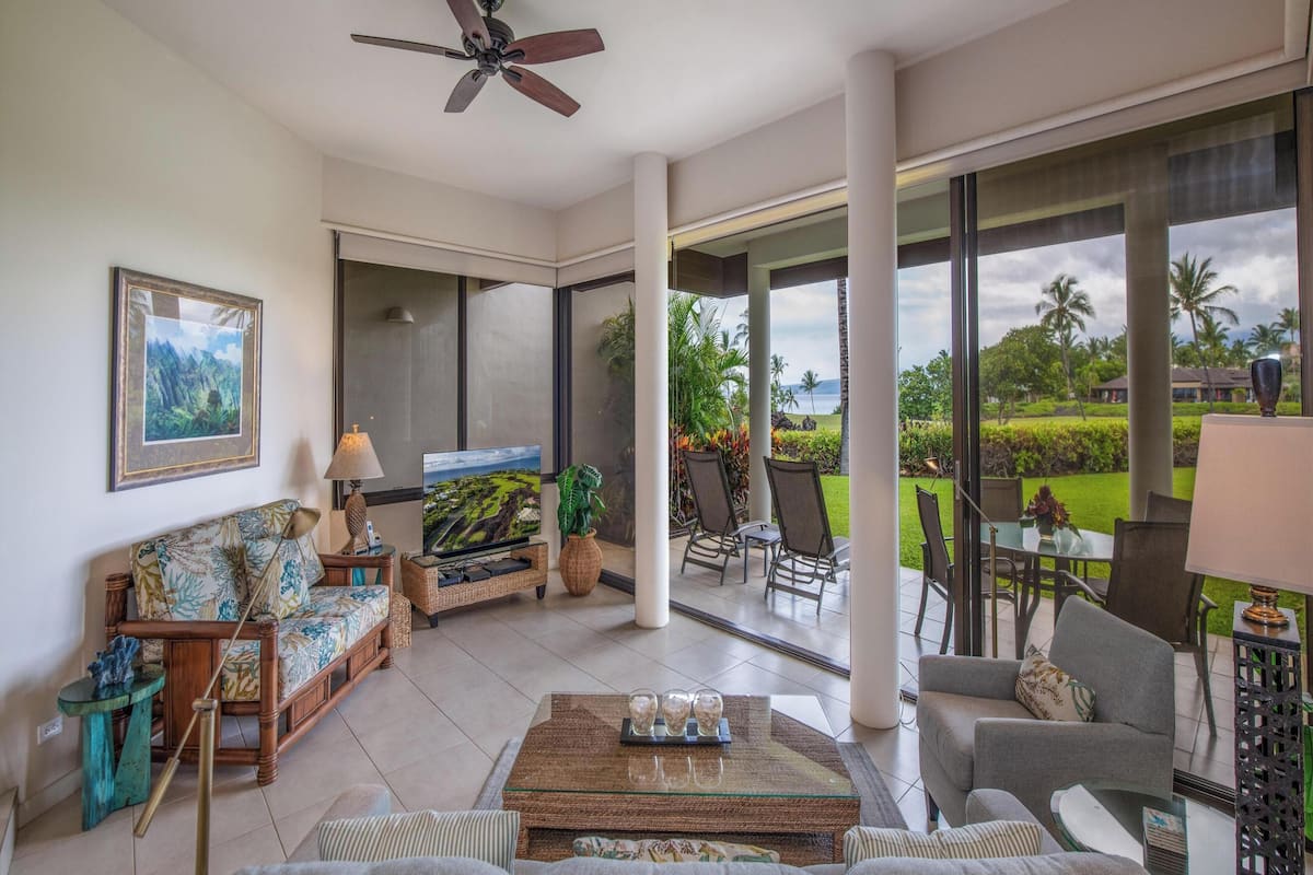 A spacious living area with a television, comfortable seating, and a view of the outdoors.