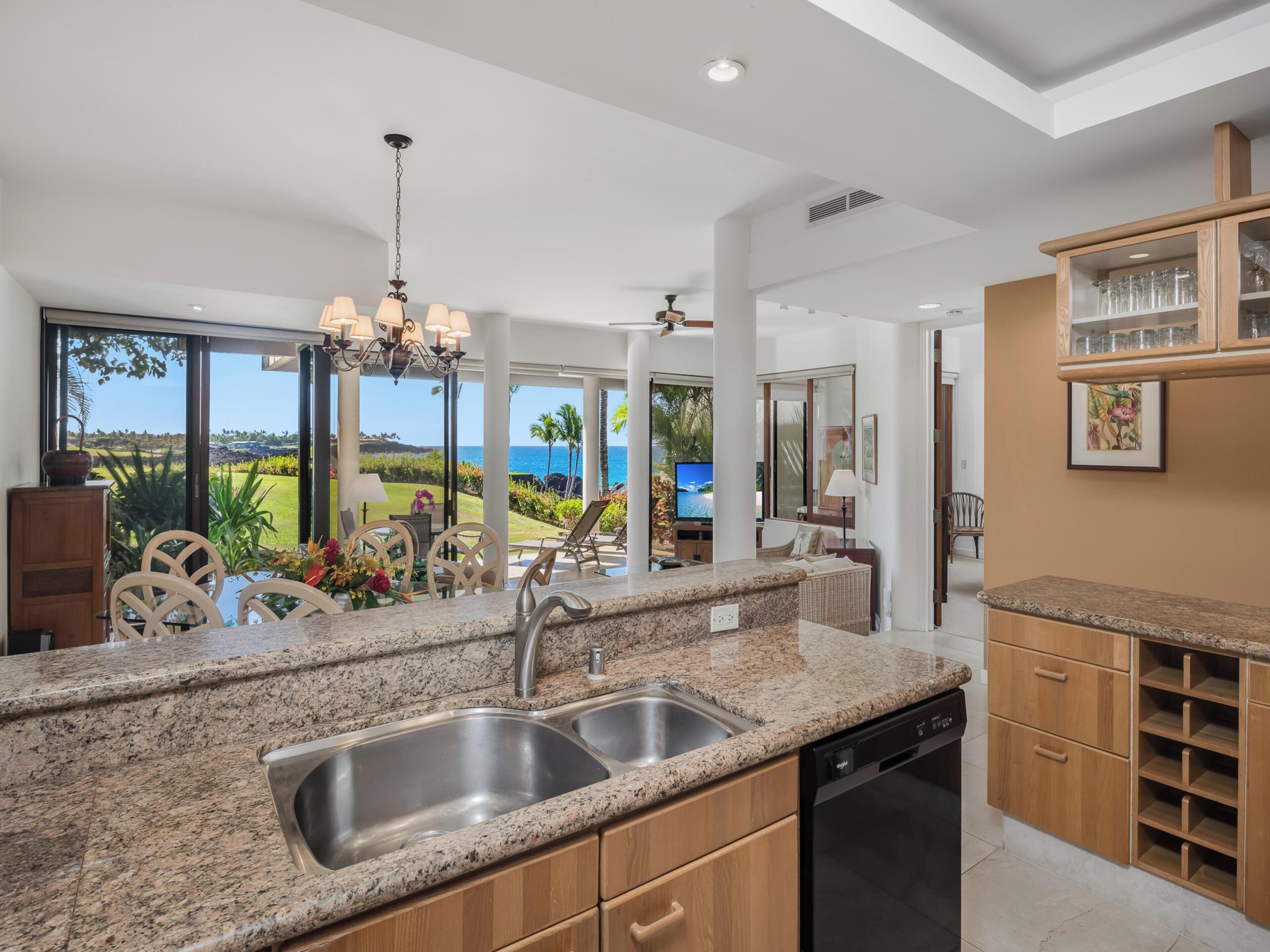 A kitchen with granite countertops, stainless steel sink, and wooden cabinets.