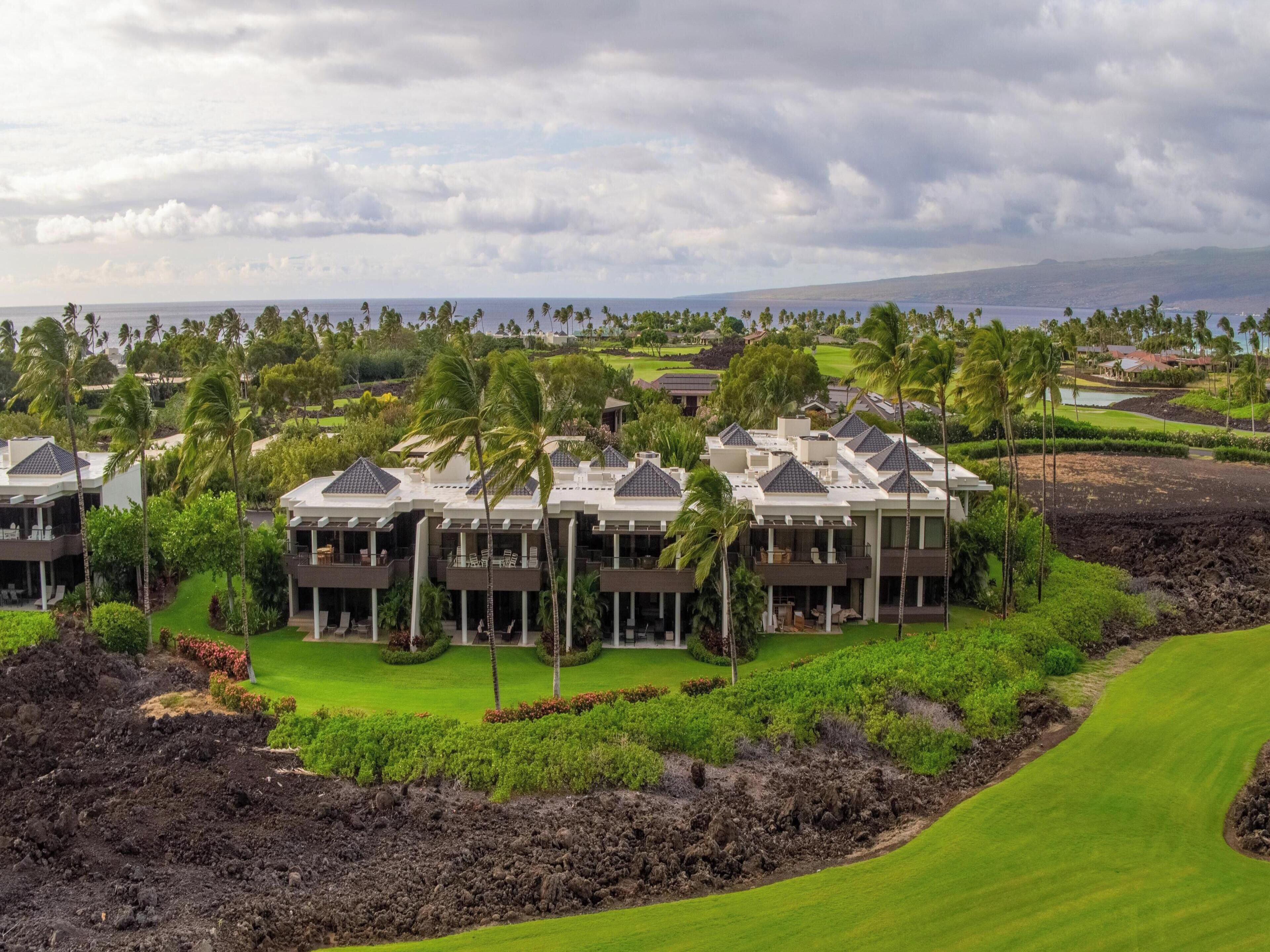 Un resort con varias edificaciones, un campo de golf y vista al océano.