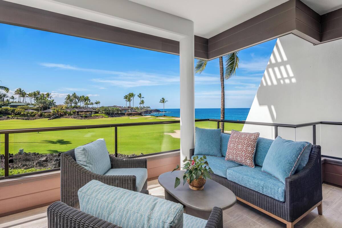 A balcony with a view of a golf course and the ocean.