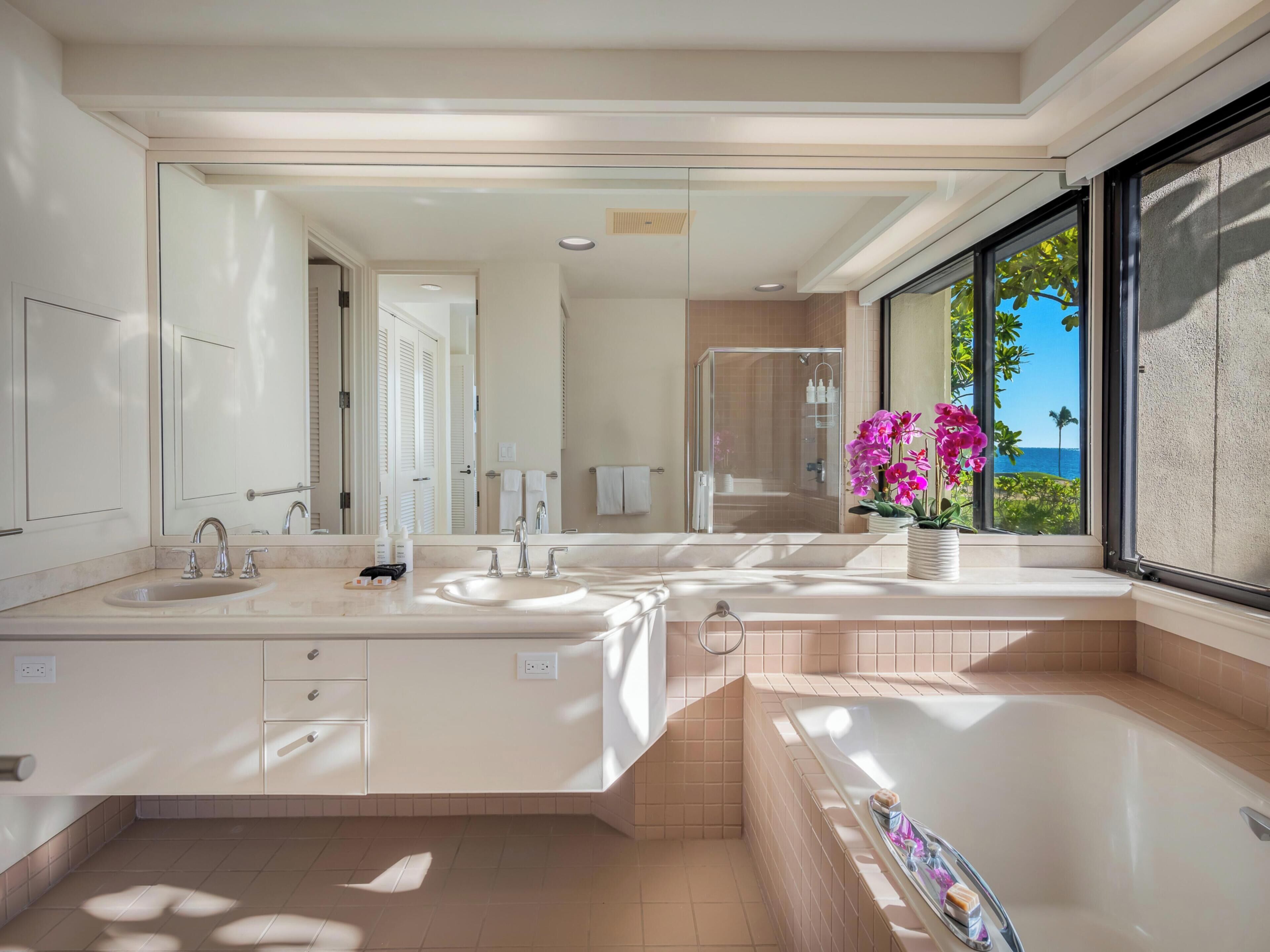 Une salle de bain moderne avec un double vasque, un grand miroir et une baignoire.