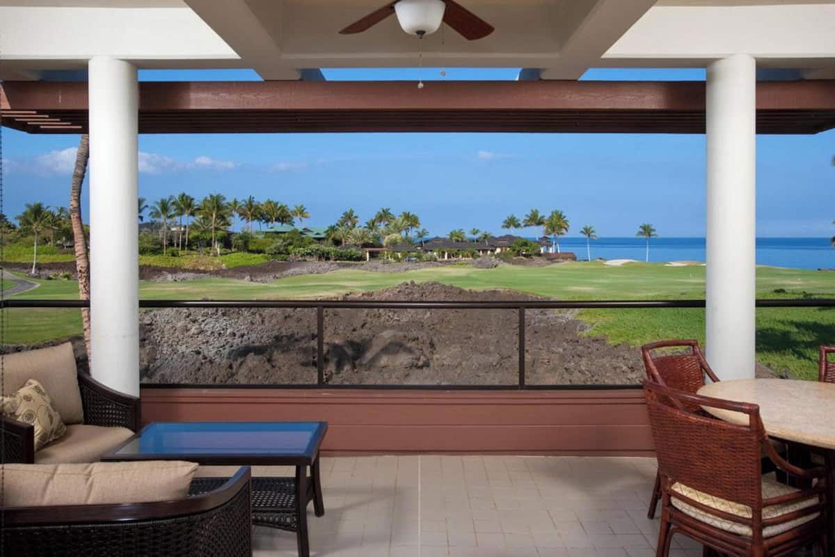 A covered outdoor area with a view of a golf course and ocean.