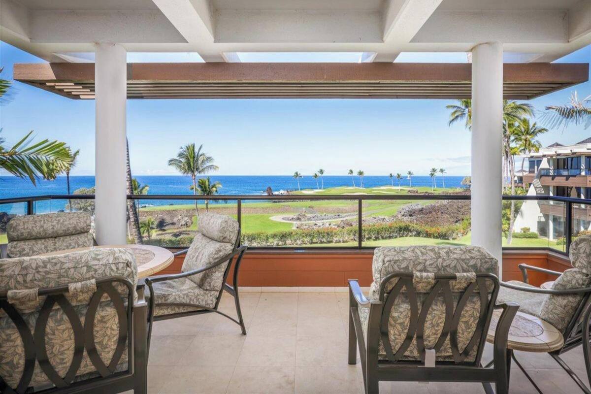 A covered outdoor seating area with a view of a golf course and ocean.