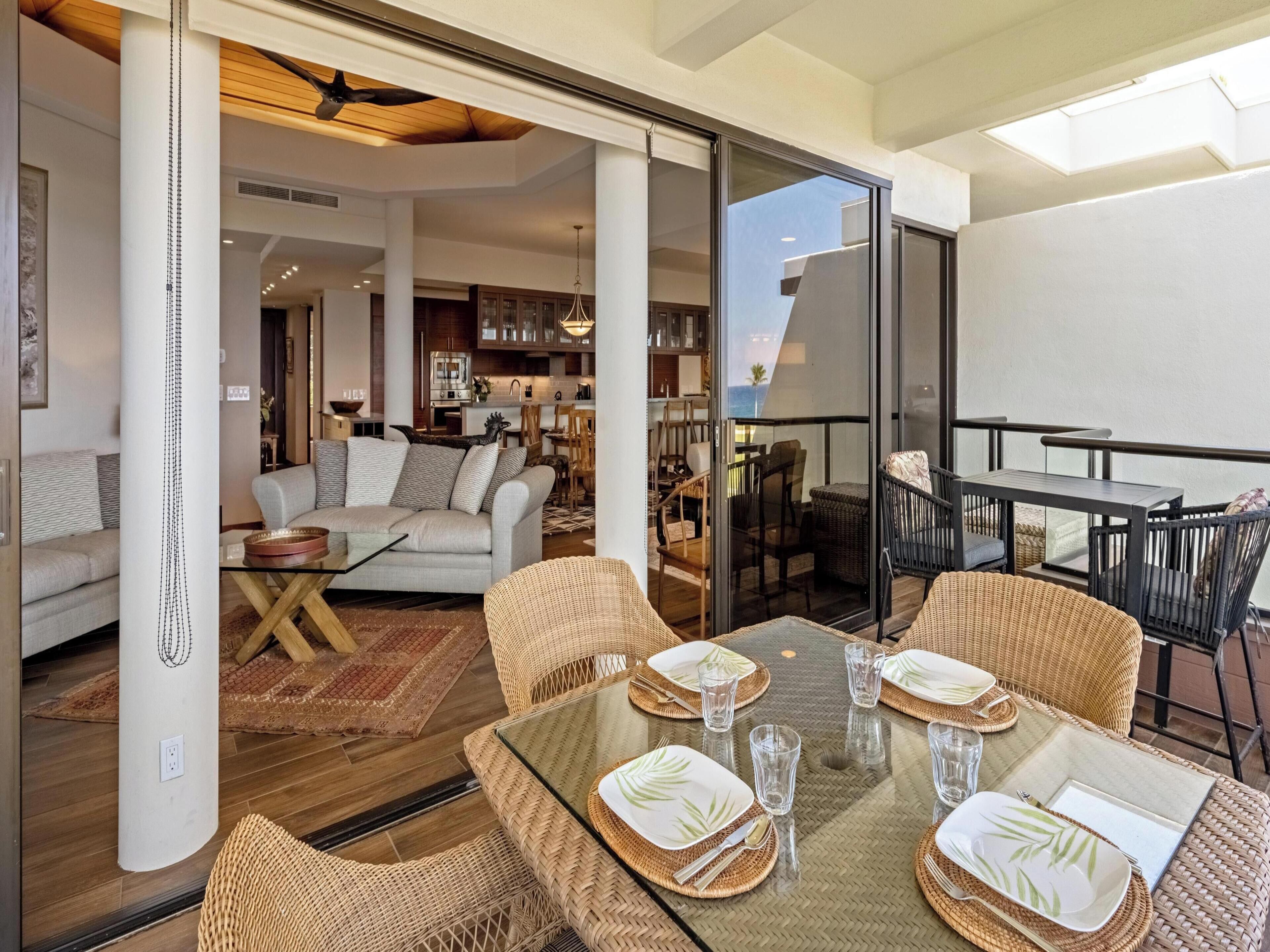 Uma sala de estar moderna com sofá, mesa de centro e área de jantar com cadeiras de vime e mesa de vidro.