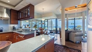 Una cucina moderna con un'isola grande, mobili in legno e vista sull'oceano.