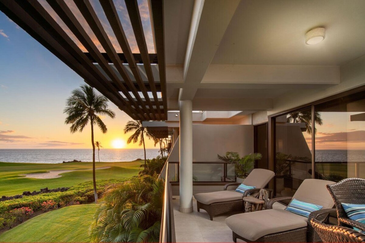 A modern outdoor balcony with a view of a golf course and the ocean at sunset.