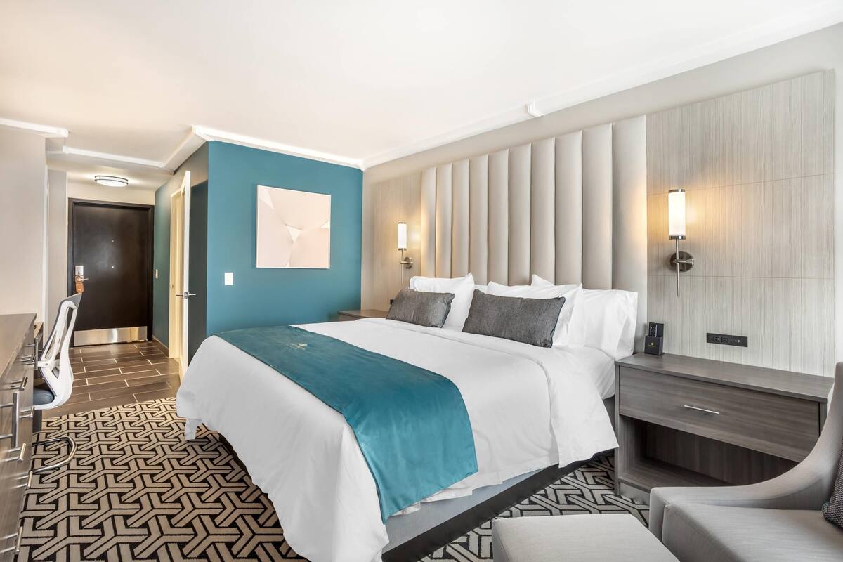 Una habitación de hotel moderna con una cama grande, un escritorio y una silla.