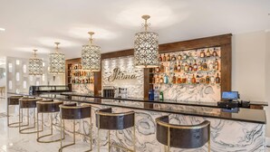 A bar area with marble countertops, bar stools, and a variety of liquor bottles. - The Ashi, an Ascend Collection Hotel (North Brunswick)