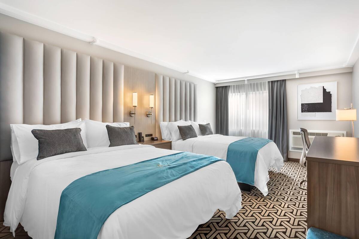 Habitación de hotel con dos camas, un escritorio y una silla.