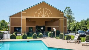 A building with a pool, a covered patio, and a parking lot.