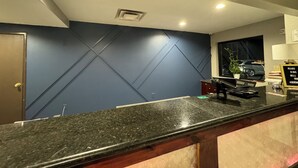 A modern kitchen with a dark blue accent wall, granite countertops, and recessed ceiling lights.