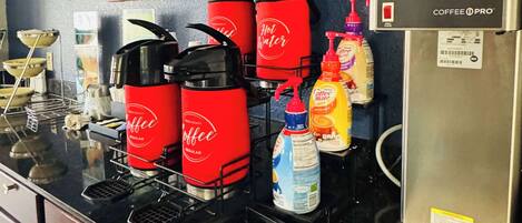 Un espace dédié au café, comprenant plusieurs machines à café et une machine à expresso, un réfrigérateur et divers accessoires liés au café.