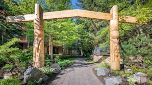 A wooden archway in a lush garden with a brick pathway leading through it.