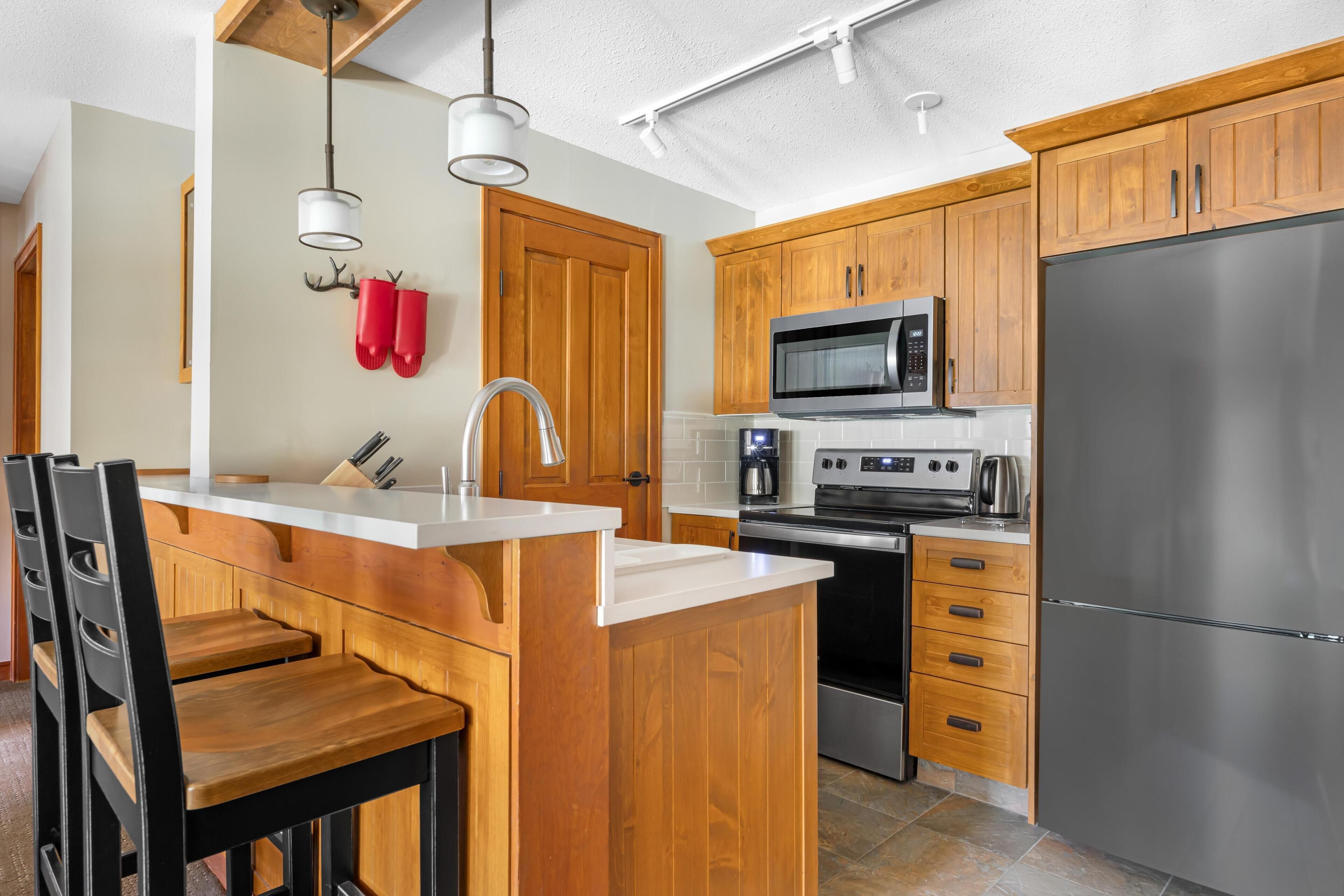 Una cocina moderna con armarios de madera, electrodomésticos de acero inoxidable y una isla con encimera blanca.