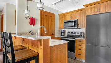 Una cocina moderna con armarios de madera, electrodomésticos de acero inoxidable y una isla con encimera blanca.