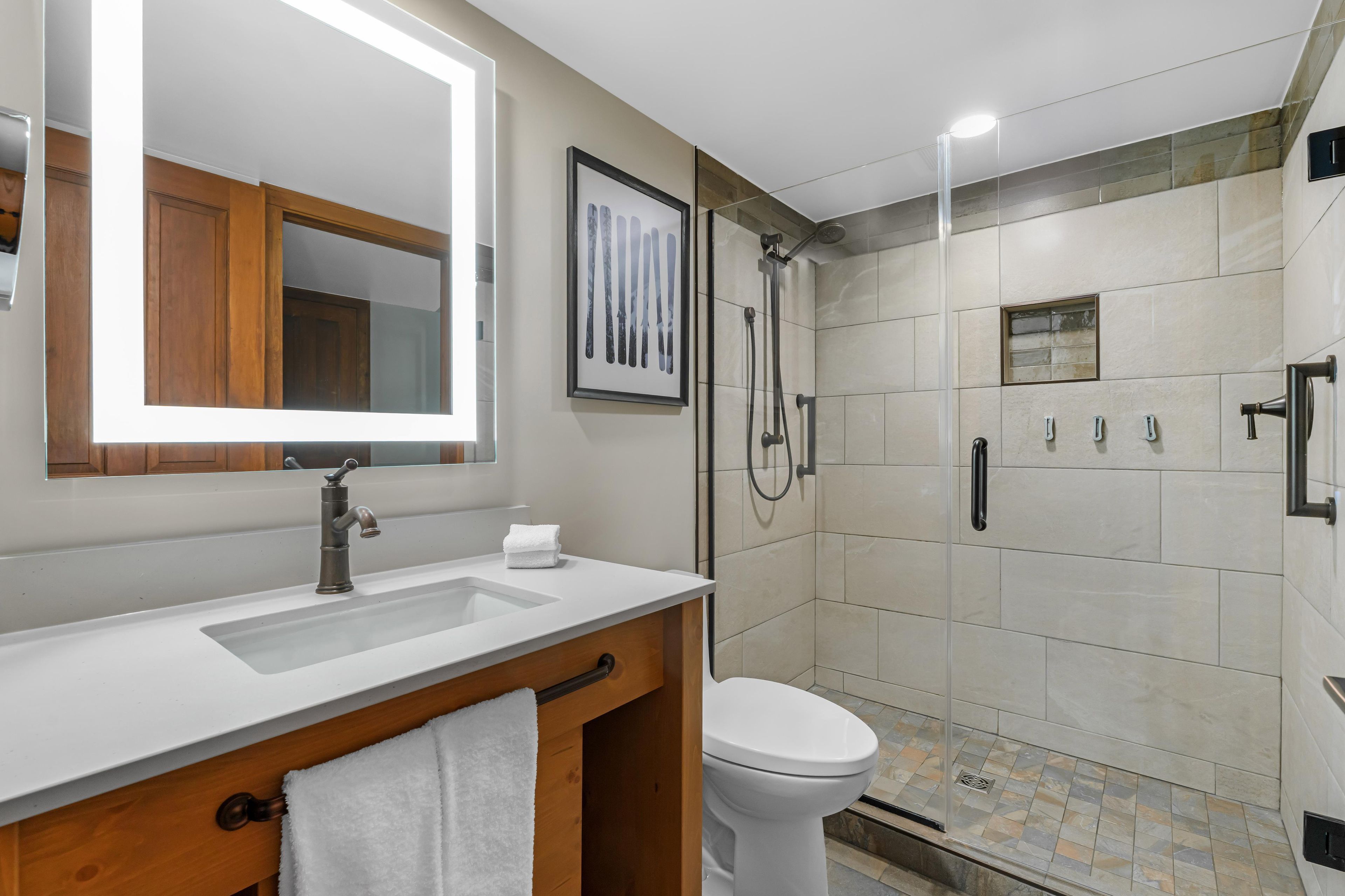 Une salle de bain moderne avec un lavabo blanc, un miroir, des toilettes et un espace douche.