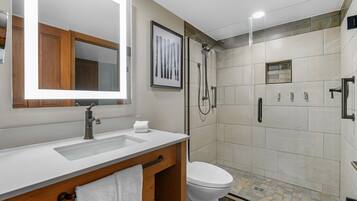 Une salle de bain moderne avec un lavabo blanc, un miroir, des toilettes et un espace douche.