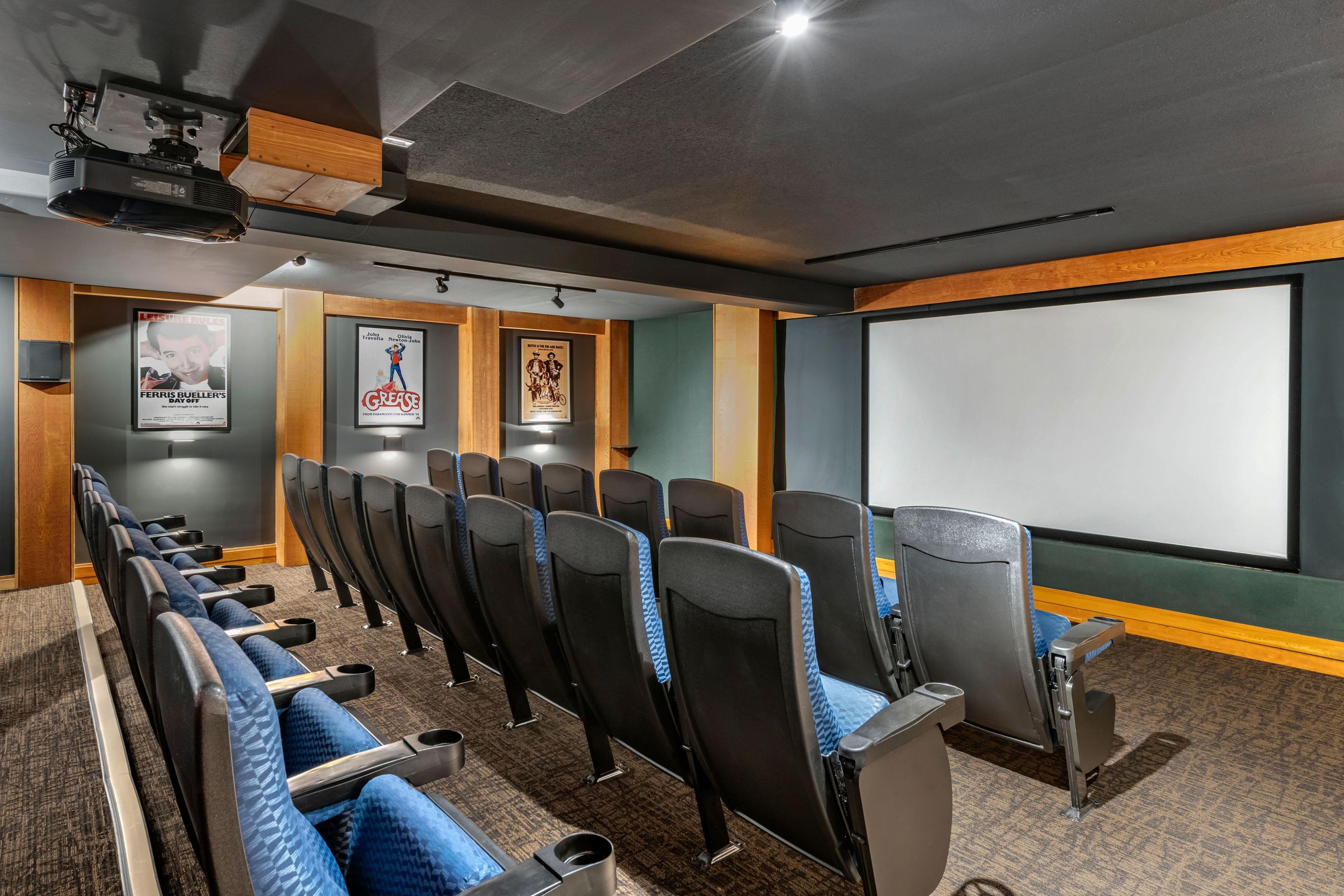 Une salle de cinéma avec des rangées de sièges, un écran et un projecteur.