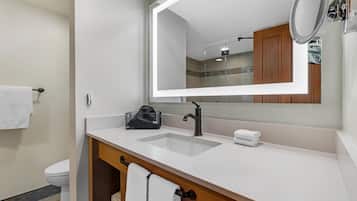 A modern bathroom with a white sink, a large mirror, and a wooden vanity.