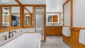 A modern bathroom with a freestanding bathtub, wooden cabinetry, and a large mirror.