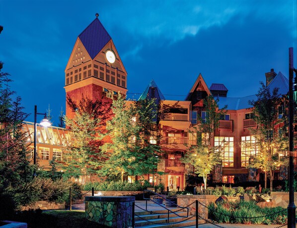 A hotel with a prominent clock tower, multiple balconies, and a well-lit courtyard.