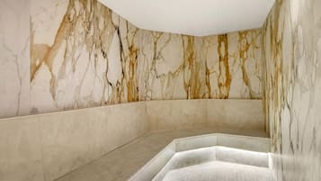 A marble-walled bathroom with a tiled floor and a built-in bench.
