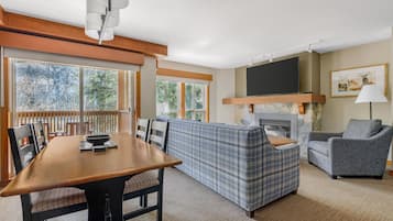 Una sala de estar con una mesa de comedor de madera, un sofá, un televisor y una chimenea.