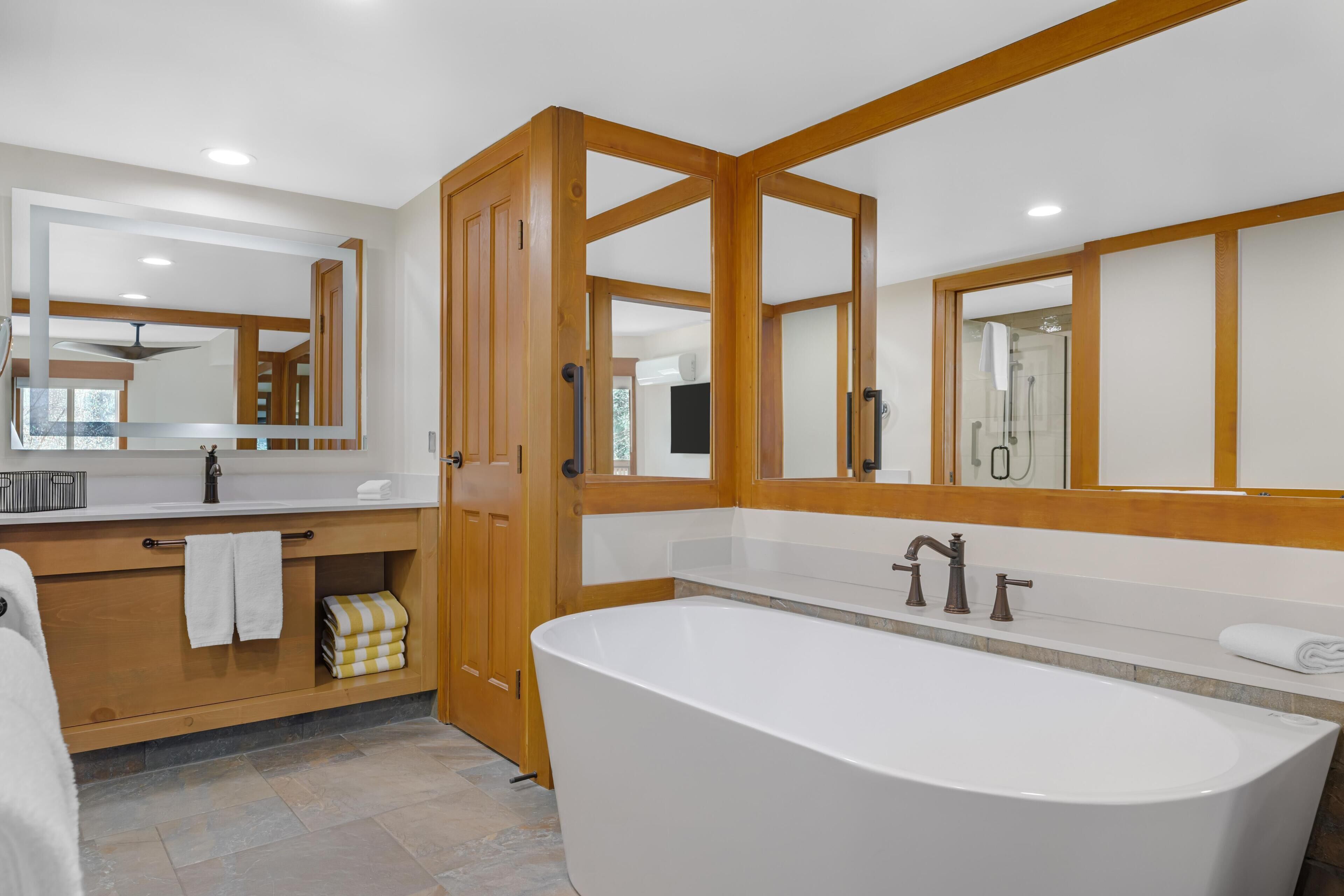A modern bathroom with a freestanding bathtub, a vanity with a mirror, and a shower area.