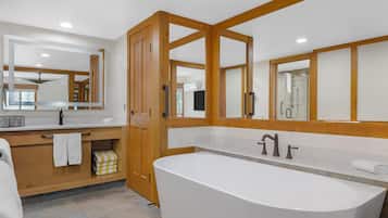 A modern bathroom with a freestanding bathtub, a vanity with a mirror, and a shower area.