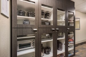 Un mueble de cocina con varios estantes que contiene electrodomésticos y recipientes de almacenamiento.