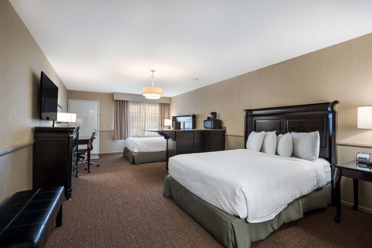 Habitación de hotel con una cama grande, un escritorio con silla, un televisor y una lámpara de escritorio.